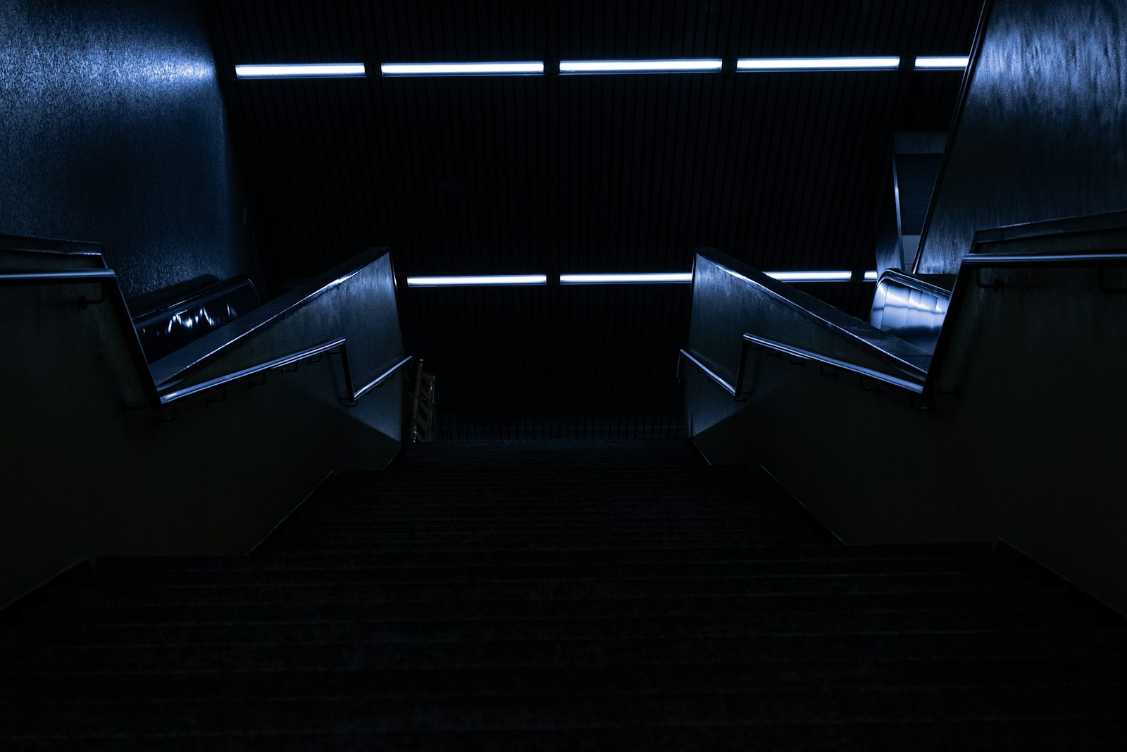 an escalator in a dark building with stairs